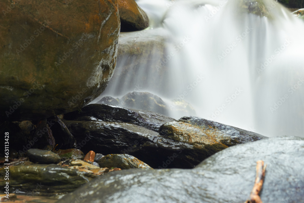 Sticker Closeup shot of wet stones with the waterfall water in the background