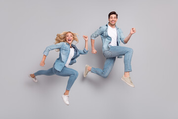 Fototapeta na wymiar Photo of funky sportive couple jump hurry run fast wear casual jeans outfit isolated grey color background