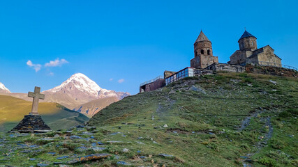 A view on Gergeti Trinity Church in Stepansminda, Georgia. The church is located on a high Caucasian mountain. Clear and blue sky above the church. In the back there are high mountain chains.