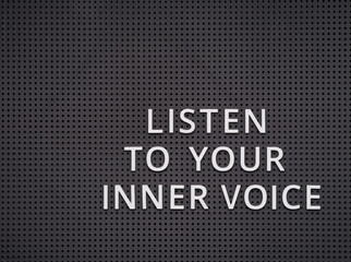 Phrase Listen to Your Inner Voice spelled out with white letters on gray pegboard