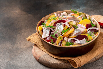 Fototapeta na wymiar Herring salad. Salad of salted herring, beetroots, potatoes, onions and cucumbers in a bowl on a dark background. Scandinavian cuisine. Copy space