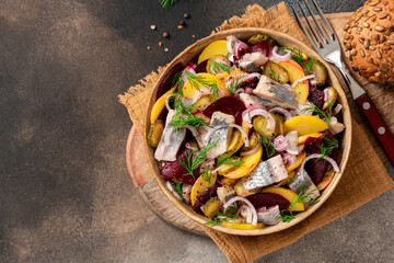 Herring salad. Salad of salted herring, beetroots, potatoes, onions and cucumbers in a bowl on a...