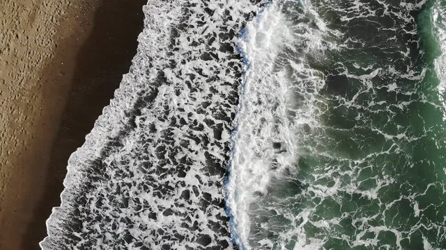 Overhead view from a drone over the beach with waves, cinematic video