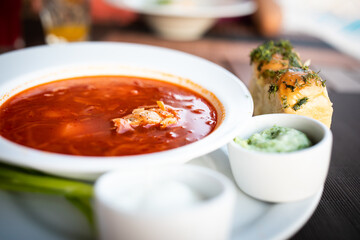 Ukrainian local meal red soup borsch with sauce and garlic buns in restaurant	