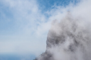 Clouds cover the rocky summit. Rocky Mountains.