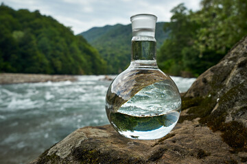 Bottle of drinking water on the shore of a mountain river.