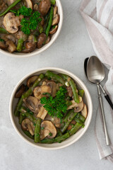 Fried brown champignons mushrooms with green beans in a creamy sauce with green onions and parsley, top view
