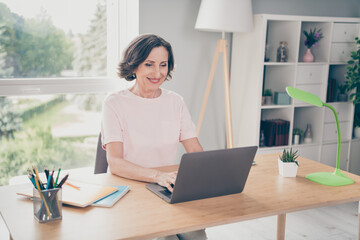 Photo portrait senior woman typing message sitting at table working on laptop at home