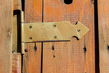 Photo of old metal hinge on wooden door surface.