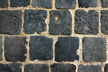 Close-up photo texture of black colored ancient brick tile road.