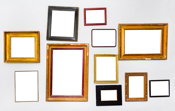 Isolated photo of various empty picture frames hanging on gray wall.