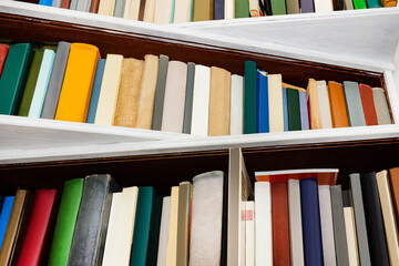 Photo of new and old various colored books standing on book shelves.