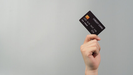 Hand is holding black credit card isolated on grey background.