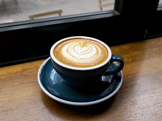 a cup of cappuccino on the wooden table by the window in a nice cafe