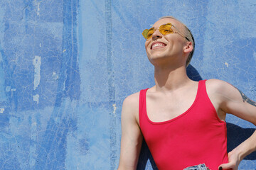 Young non-binary person wearing sunglasses and smiling while posing outdoors.