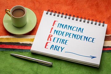 FIRE acronym - financial independence, retire early, handwriting in a sketchbook with a cup of...