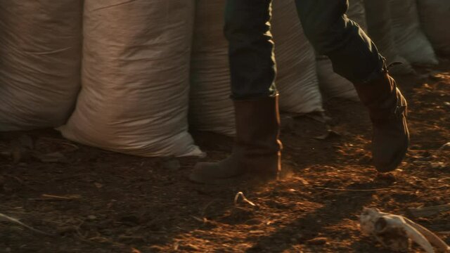 Unrecognizable farmer walking near bags