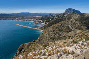 Fototapeta na wymiar View of the blue mediterranean sea and a port of a coastal city and a beautiful mountain landscape in Spain