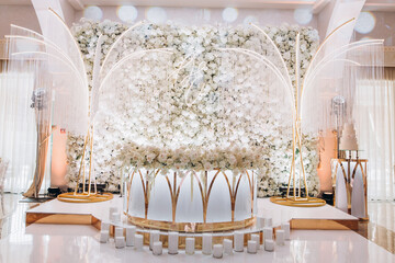 Huge wedding table for the bride and groom decorated with white flowers, candles, white fountains. White and gold colours