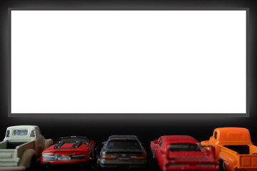 Concept of car cinema,drive-in, with several five pickup truck type toy cars,back view,large white...