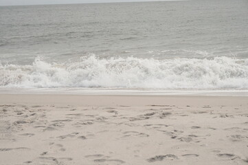 Gray Blue Ocean Waves with White Caps Breaking on Sandy Beach in Daylight