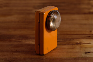 Old flashlight on a wooden background. 