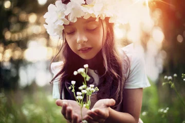 Fotobehang Portrait of cute kid girl with bloom flowers. Nature outdoor. Child in nature concept. © konradbak