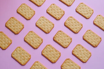 Obraz na płótnie Canvas Crackers or biscuits arranged in rows on pink background, isolated