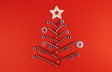 Christmas tree made of metal bolts, screws and self-tapping screws, decorated with nuts and washers with a wooden star on a red background. Symbol of the new year