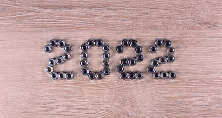 Number 2022 by metal nuts on a light wooden background. 2022 year