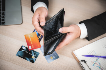 High angle closeup view of hands of a businessman in formal clothing looking at an empty wallet...
