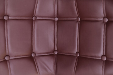 Corner background of a brown leather sofa or armchair covered with leather buttons. The texture of a vintage Chesterfield sofa.