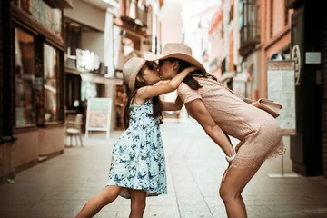 Poster Loving mother and her cute daughter exploring city on a sunny summer day. © konradbak