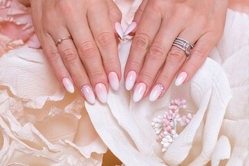 
Female hands with ombre manicure nails, pink gel polish, on paper flowers background - obrazy, fototapety, plakaty