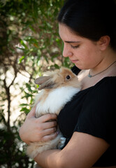 Young beautiful woman holding a black rabbit pet animal. Domestic animal caring