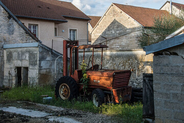 old rusty tractor near an old house in the French village Arc en Barrois in the region Champagne Ardenne on a summer evening 