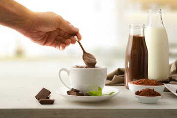 Hand stirring freshly prepared hot chocolate on kitchen bench front