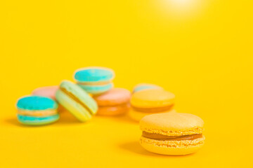 Fototapeta na wymiar Sweet almond colorful unicorn pink blue yellow green macaron or macaroon dessert cake isolated on trendy yellow modern fashion background. French sweet cookie. Minimal food bakery concept Copy space
