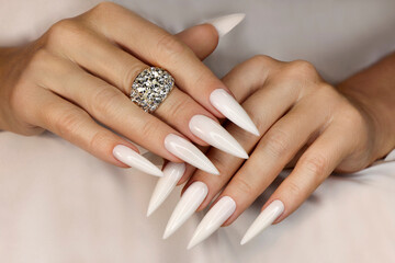 Long light manicure with jewelry on a woman's hand. - obrazy, fototapety, plakaty