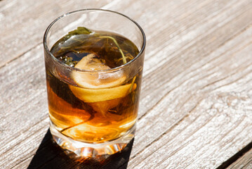 glass cup with tea, lemon and mint on a gray-brown wooden surface, light shadow, sunlight of morning tea, top view, isolated on wooden background 