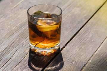 glass cup with tea, lemon and mint on a gray-brown wooden surface, light shadow, sunlight of morning tea, top view, isolated on wooden background 