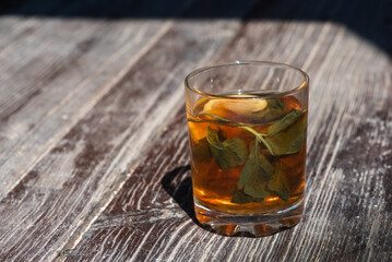 glass cup with tea, lemon and mint on a gray-brown wooden surface, light shadow, sunlight of morning tea, top view, isolated on wooden background 