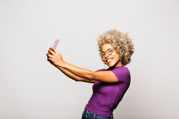 Portrait of Smiling Young woman using smart phone with a rainbow flag case while standing Against...