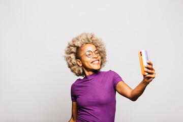 Portrait of Smiling Young woman using smart phone with a rainbow flag case while standing Against...