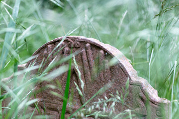 Graves and tombstones in the old cemetery in the park in the fog and rain in the morning. Hands carved into the tombstone.