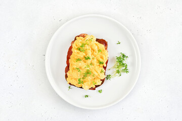 Scrambled eggs with microgreen and bacon on bread