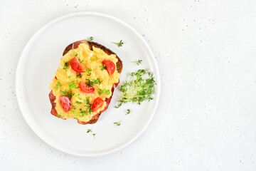 Scrambled eggs with microgreen and tomatoes on bread