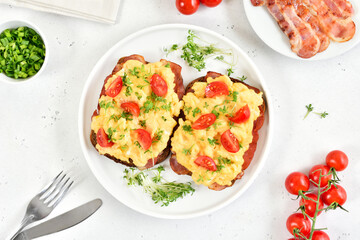 Scrambled eggs with microgreen and tomatoes on bread