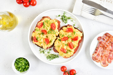 Scrambled eggs with microgreen and tomatoes on bread