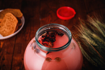 Jar of homemade bread and hibiscus kvass, wheat ears, slices of rye bread on wooden background. Traditional Ukrainian beverage, closeup shot